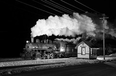 steam train passing a small passenger shelter