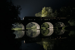 silhouette of a train on an arch bridge