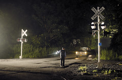 railroad crew stops traffic with lantern at a flagging-crossing-night