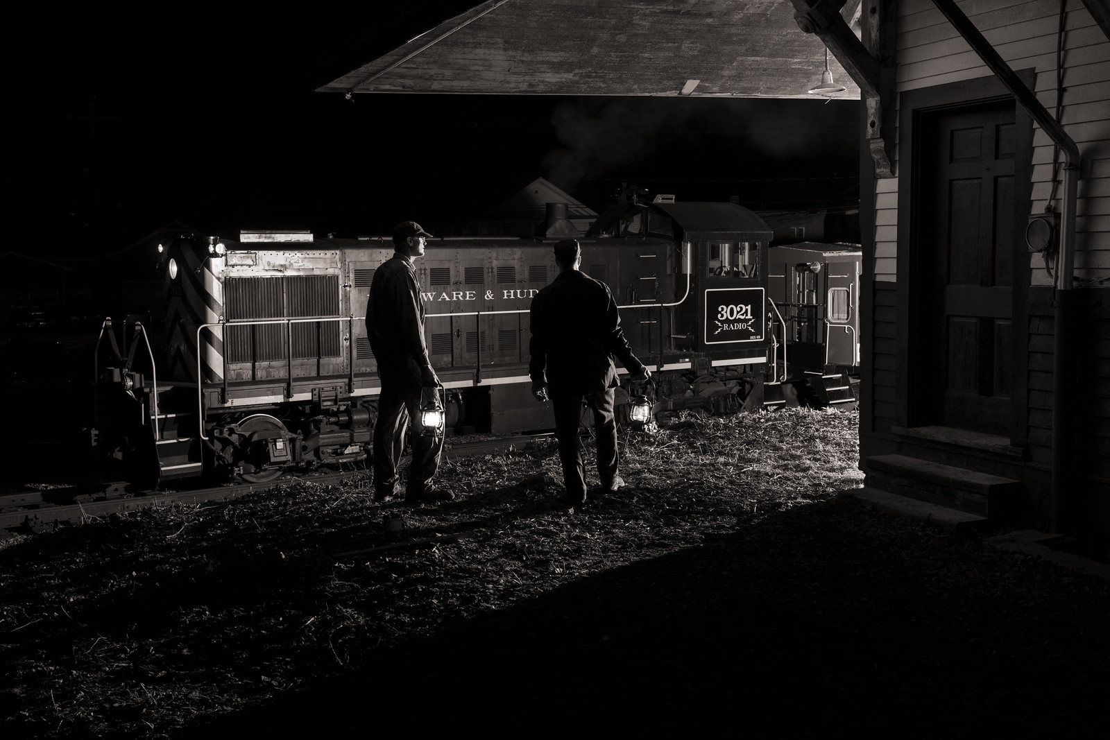 locomotive and its crew with lanterns at a depot