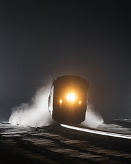 train passes over a snow covered river at night