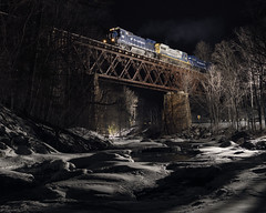 train passes over a snow covered river at night