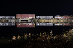 reflections of freightcars in still water at night