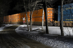 A wall of oranage and blue containers on a train cut through the woods